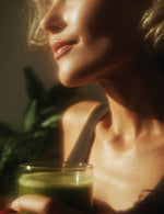 Zbliżenie kobiety trzymającej szklankę zielonego napoju z Bio Chlorella Biowen.