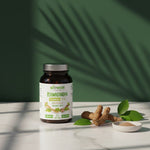 Suplement Biowen Ashwagandha ustawiony obok korzeni, liści i miseczki z proszkiem w naturalnym świetle.