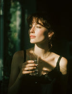 Kobieta w świetle słońca pije elektrolity Biowen Vital Charge+ z przezroczystej szklanki