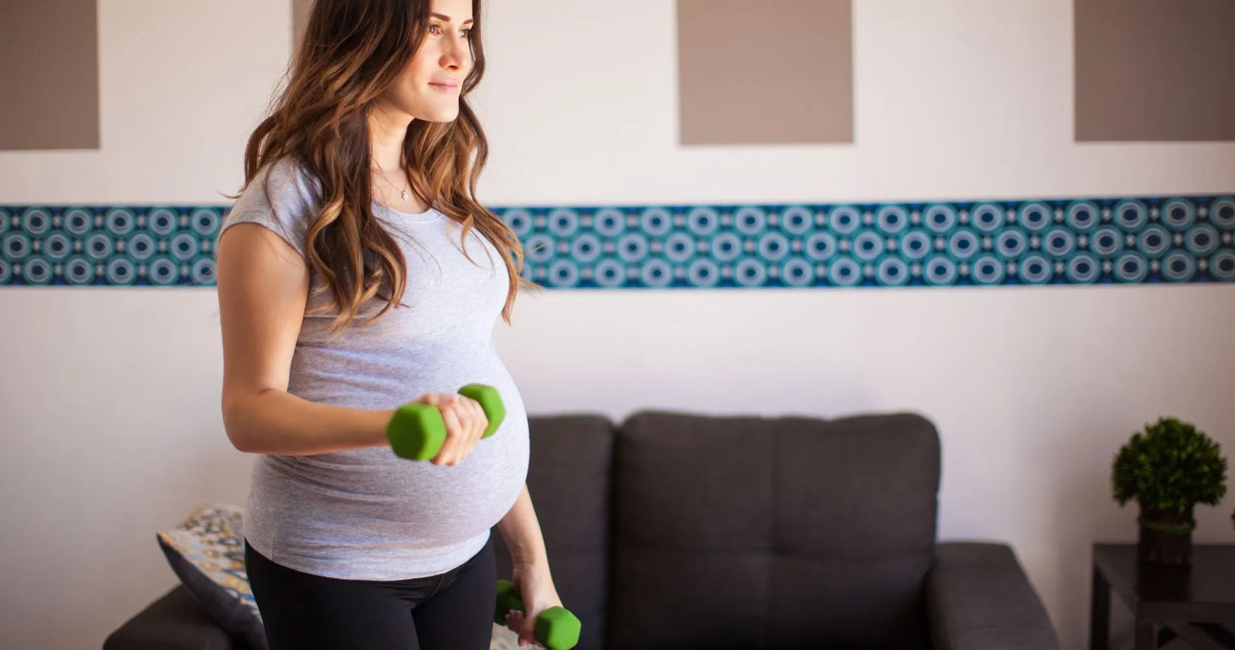Kobieta w ciąży ćwicząca z hantlami w domu – bezpieczna aktywność fizyczna w ciąży.
