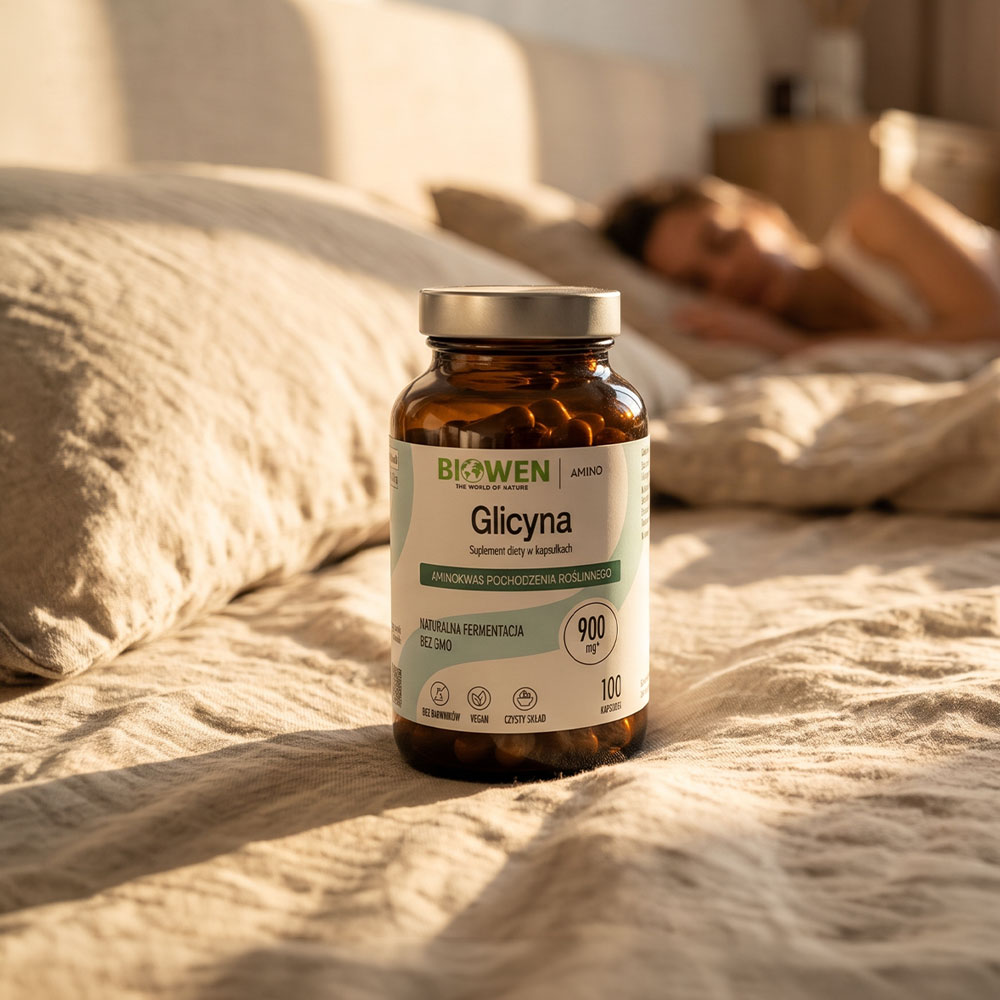 Glicyna Biowen 900 mg, suplement diety w kapsułkach, opakowanie 100 kapsułek stojące na łóżku, w tle odpoczywająca kobieta.
