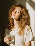 Kobieta w świetle słońca z napojem Elektrolity Vital Charge+ Biowen malinowe.