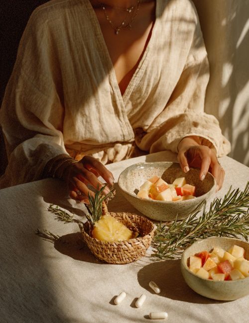 Osoba w lnianej koszuli przy stole z miseczkami owoców i kapsułkami Biowen EnzyMax Complex+