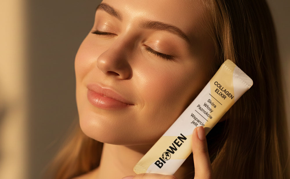 Zbliżenie twarzy kobiety o promiennej, zdrowej skórze, trzymającej przy policzku beżową saszetkę Collagen Elixir Biowen z napisem o wsparciu skóry, włosów, paznokci i jelit