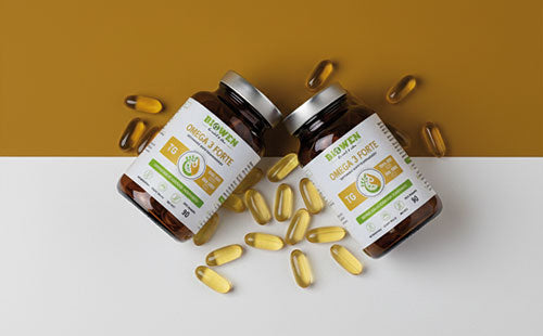 Dwa opakowania suplementu Omega 3 Forte Biowen 60 kapsułek z rozsypanymi żółtymi kapsułkami.