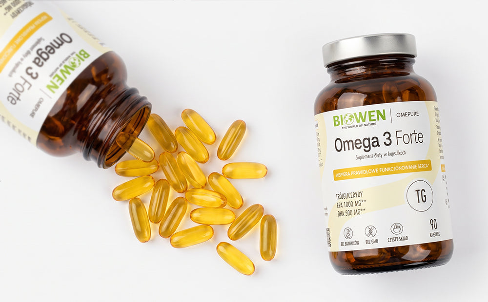 Dwa opakowania suplementu diety Biowen Omega 3 Forte 90 kapsułek oraz rozsypane kapsułki z olejem rybim.