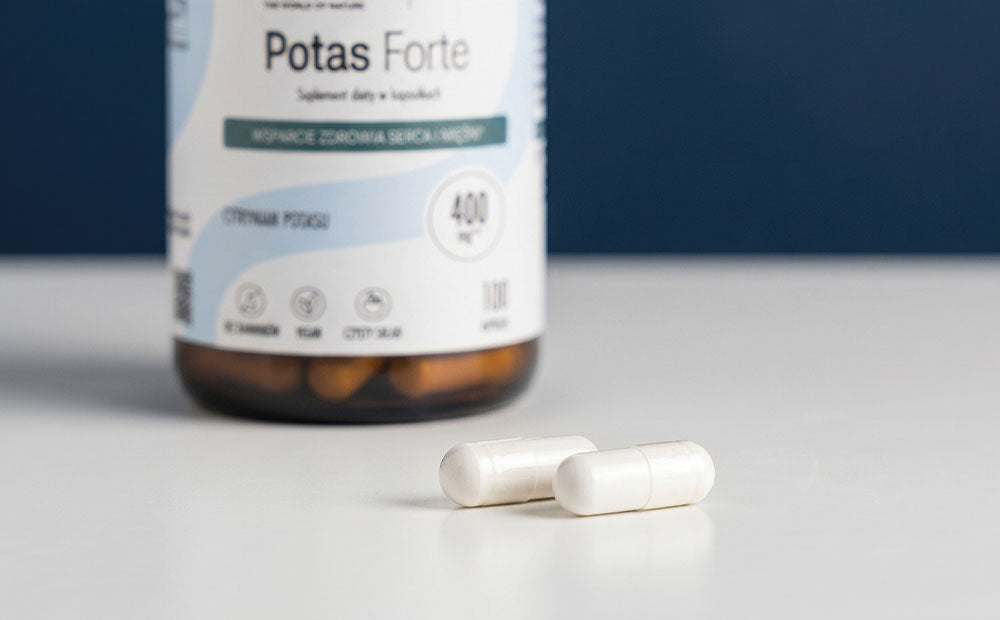 Dwie białe kapsułki Biowen Potas Forte 400 mg na tle opakowania produktu