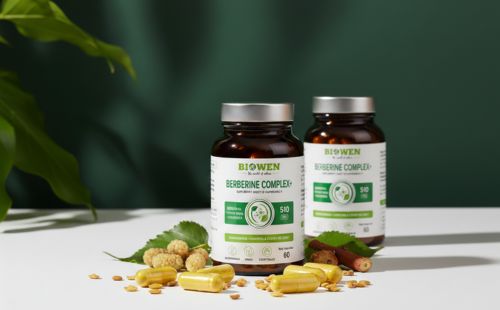 Dwa opakowania Berberyna Complex+ Biowen 60 kapsułek z żółtymi kapsułkami, liśćmi i owocami morwy na białym blacie.