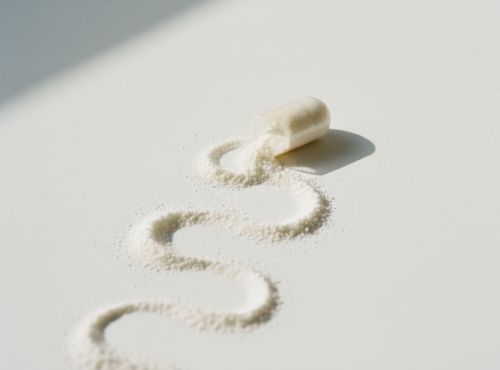 Otwarta kapsułka magnezu z potasem Biowenz rozsypanym białym proszkiem tworzącym krętą linię na białym tle.