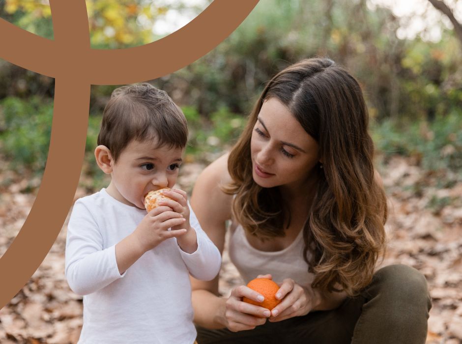 Mama z dzieckiem jedzącym mandarynkę, naturalne źródło witaminy C.