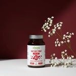 Suplement diety Niacyna (witamina B3) Biowen Proszek 120 g w brązowym słoiczku, ustawiony na białym stole z gałązką drobnych białych kwiatów na bordowym tle.