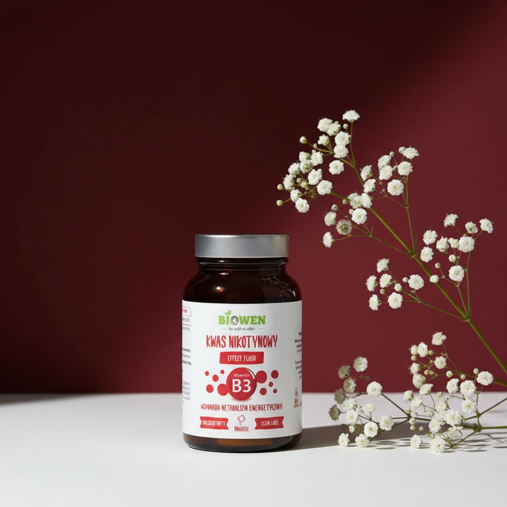Suplement diety Niacyna (witamina B3) Biowen Proszek 120 g w brązowym słoiczku, ustawiony na białym stole z gałązką drobnych białych kwiatów na bordowym tle.