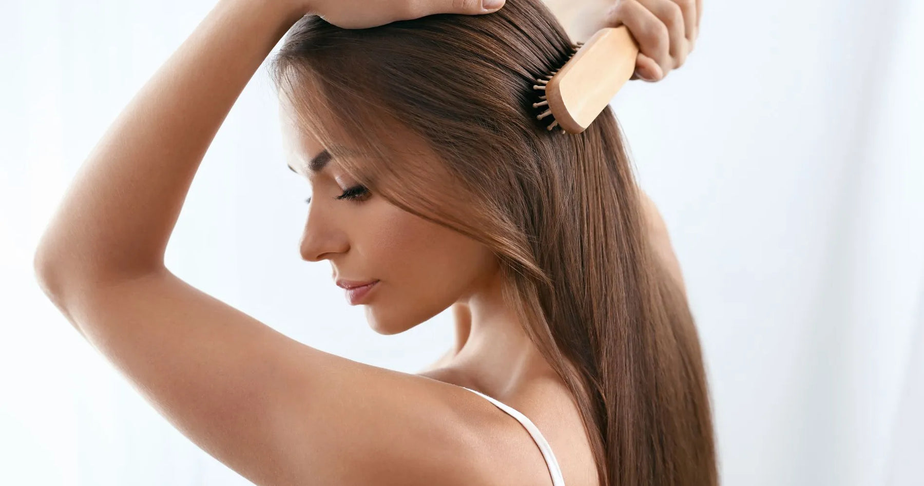 Kobieta szczotkująca długie, lśniące włosy – codzienna pielęgnacja przy przetłuszczających się włosach.