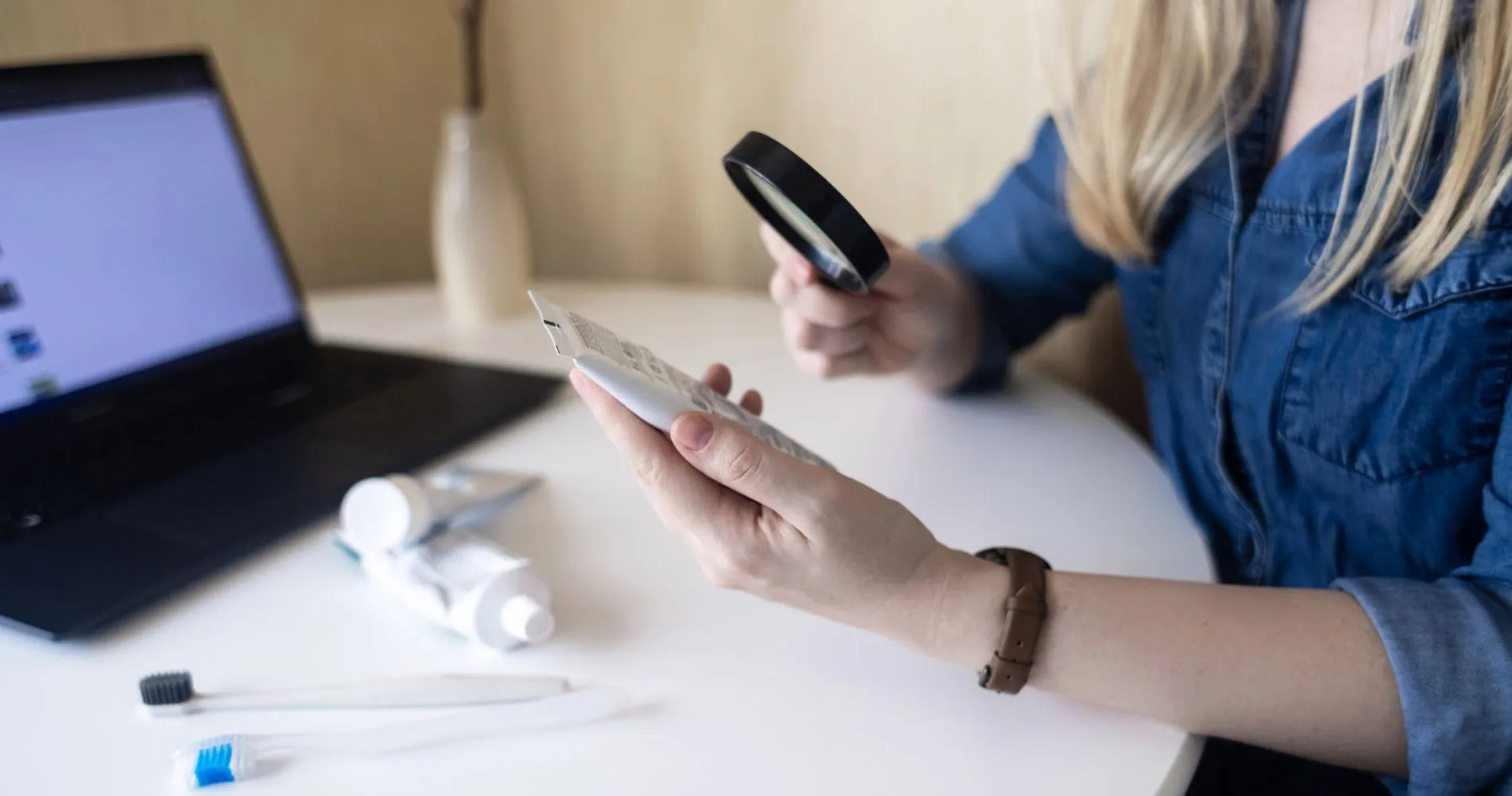 Kobieta czytająca skład kosmetyku przez lupę, symbol świadomego wyboru produktów z SLS i SLES.