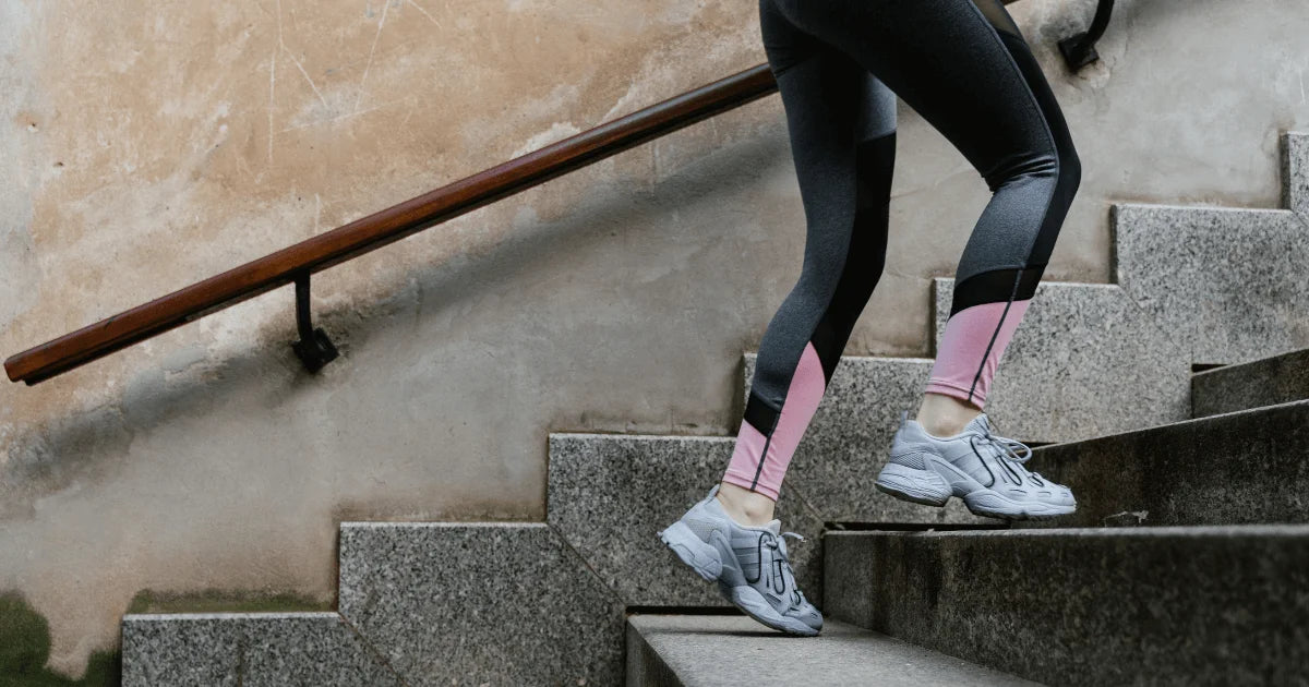 Kobieta w sportowym stroju wbiega po schodach, symbolizując energię i dobre samopoczucie wspierane witaminami dla kobiet.