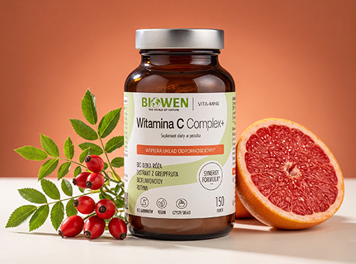 Witamina C Complex+ Biowen 150 g, suplement diety w proszku z dziką różą, ekstraktem z grejpfruta, bioflawonoidami i rutyną, obok owoców dzikiej róży i grejpfruta.