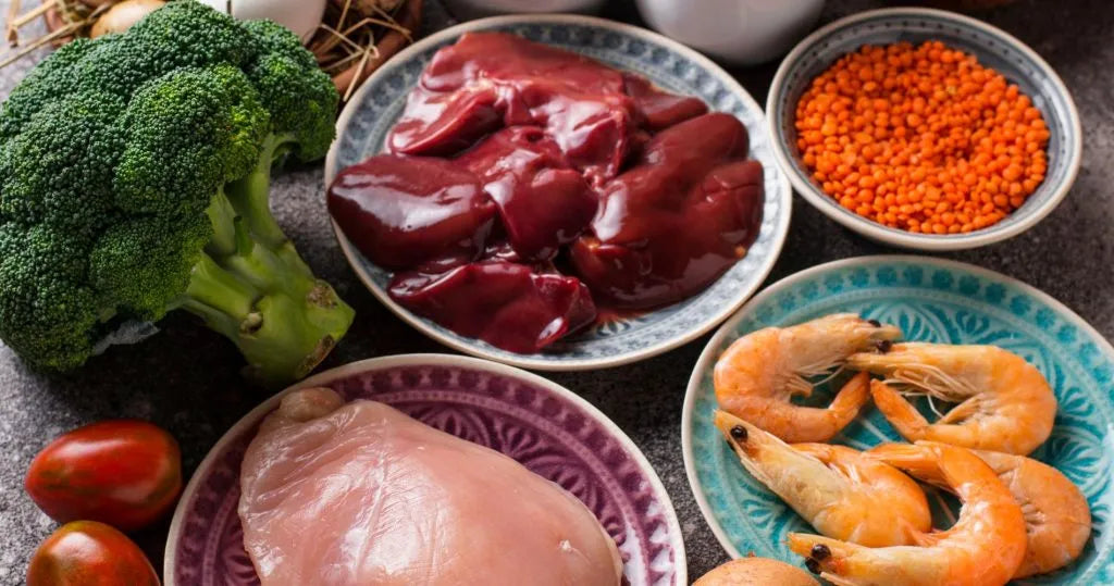 Żywność bogata w chrom – świeże warzywa, wątróbka, drób, owoce morza i rośliny strączkowe na kolorowych talerzach.